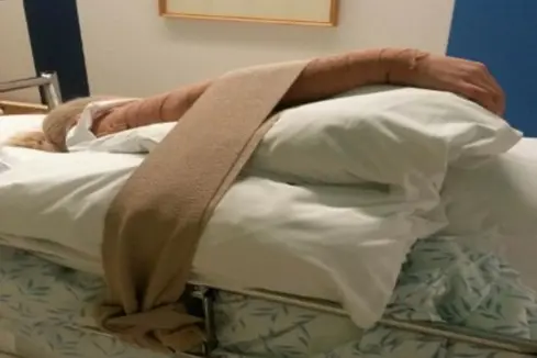 En person som ligger på en seng med sikring av armen