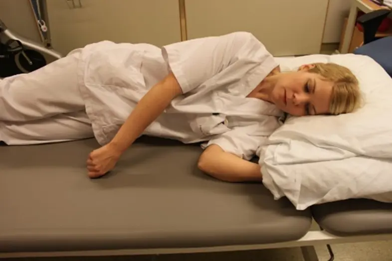 En person som ligger på siden på en sykehusseng