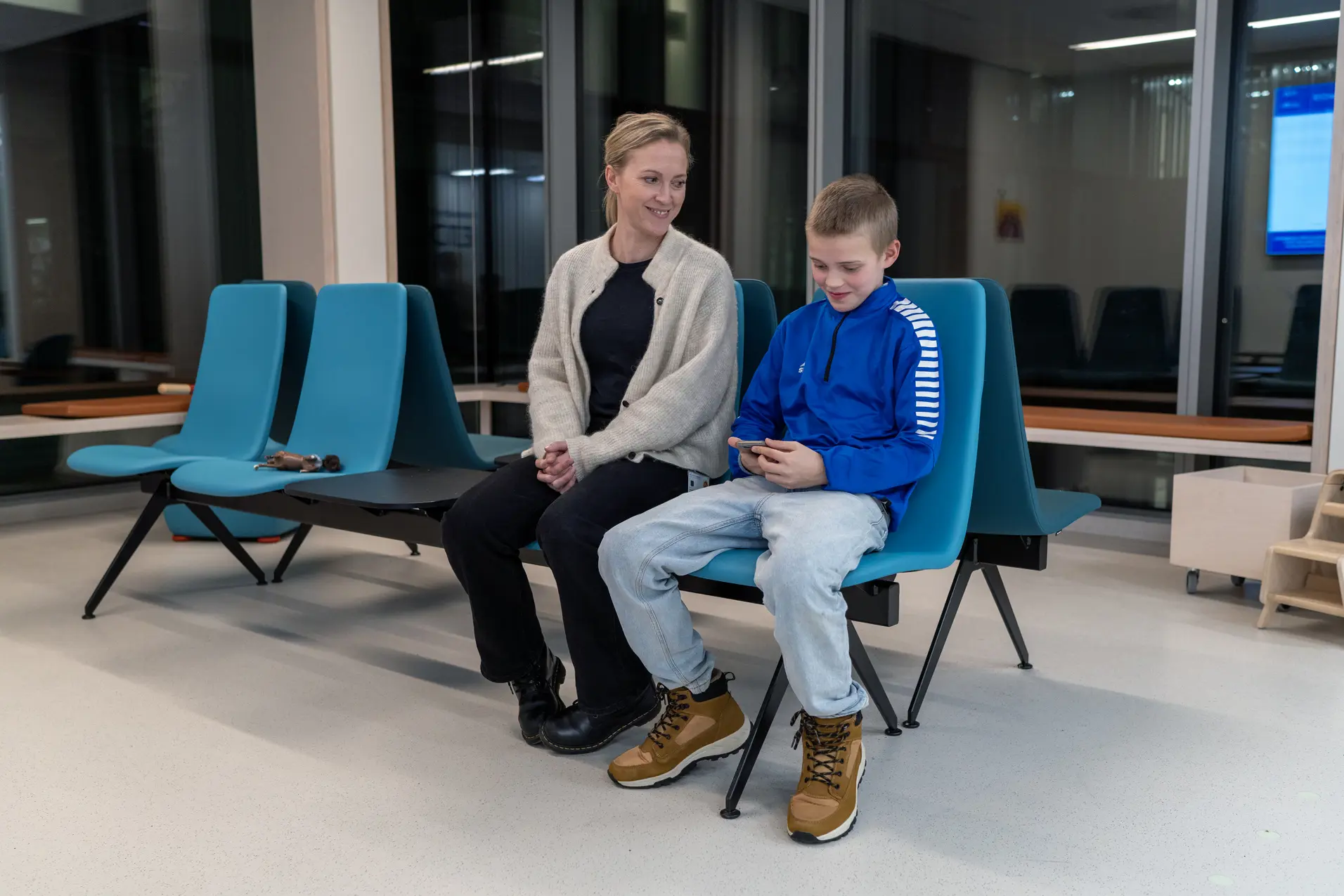 Mor og sønn som sitter på et venterom på sykehuset