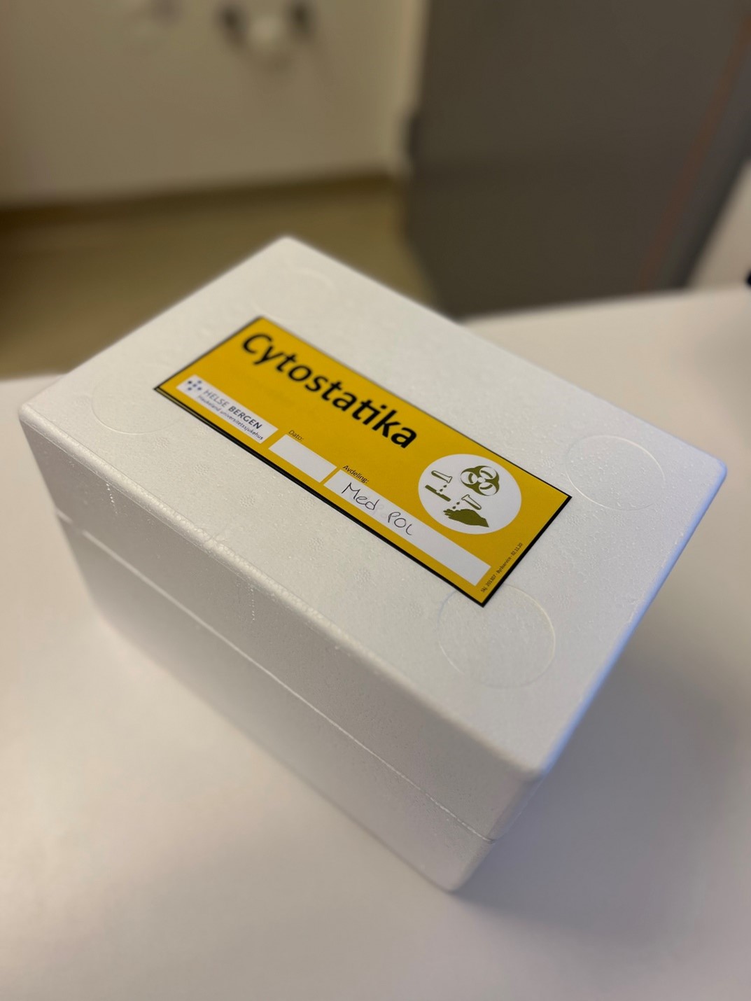 En hvit boks cytostatika med gul merkelapp på.