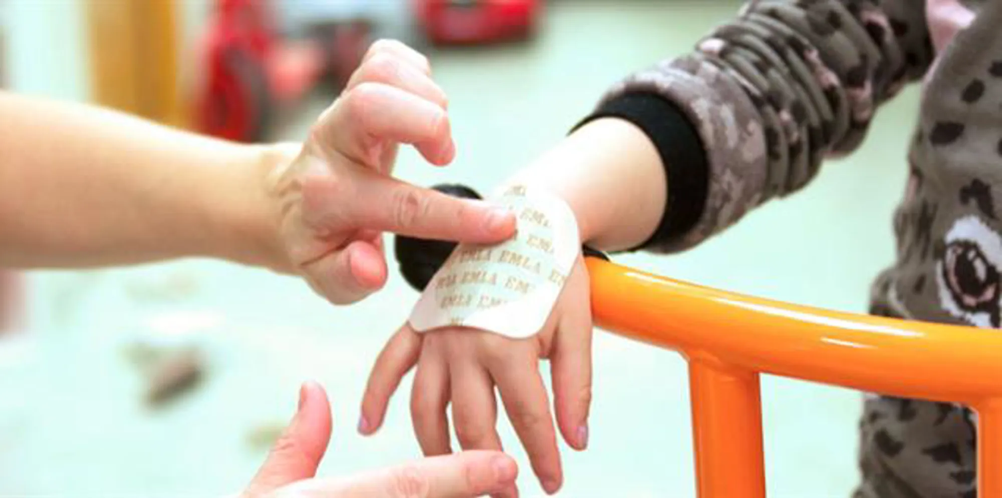 Et barn som får emla-plaster på hånden