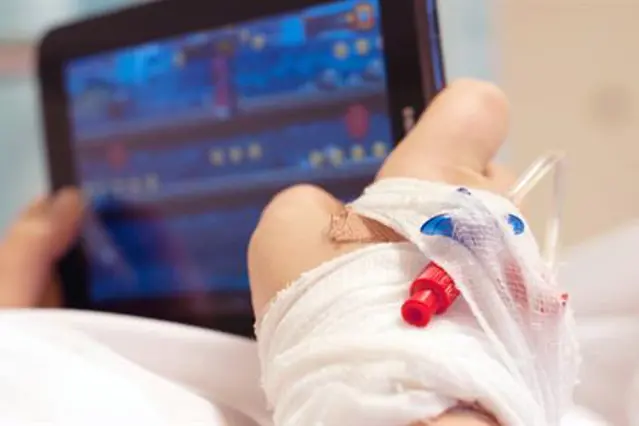 En hånd som holder et lite hvitt kosedyr foran en dataskjerm