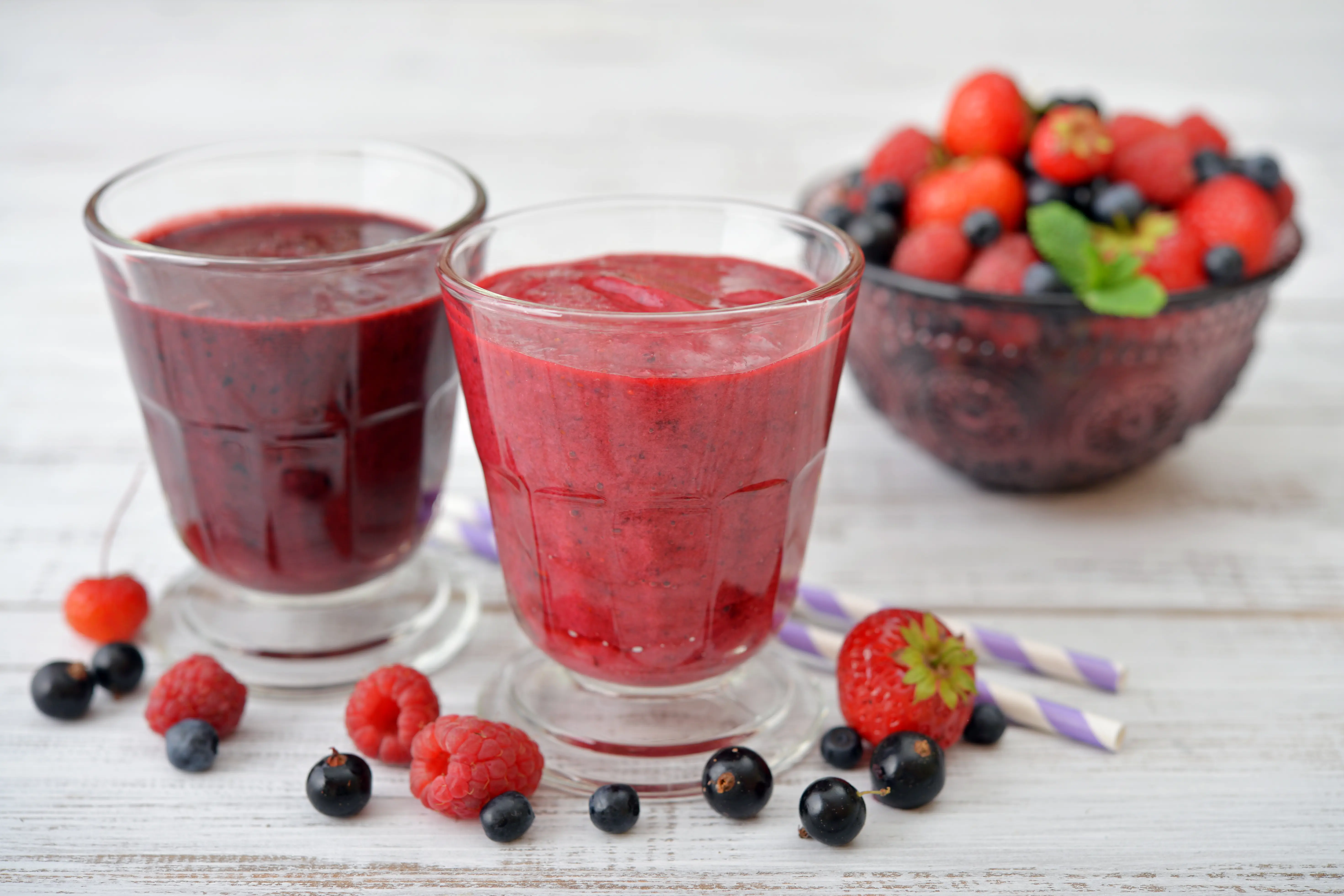 Bilde av to smoothies og ei skål med jordbær og blåbær