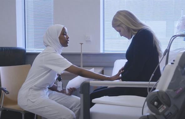 Jordmor tar på gravid kvinne sin mage.