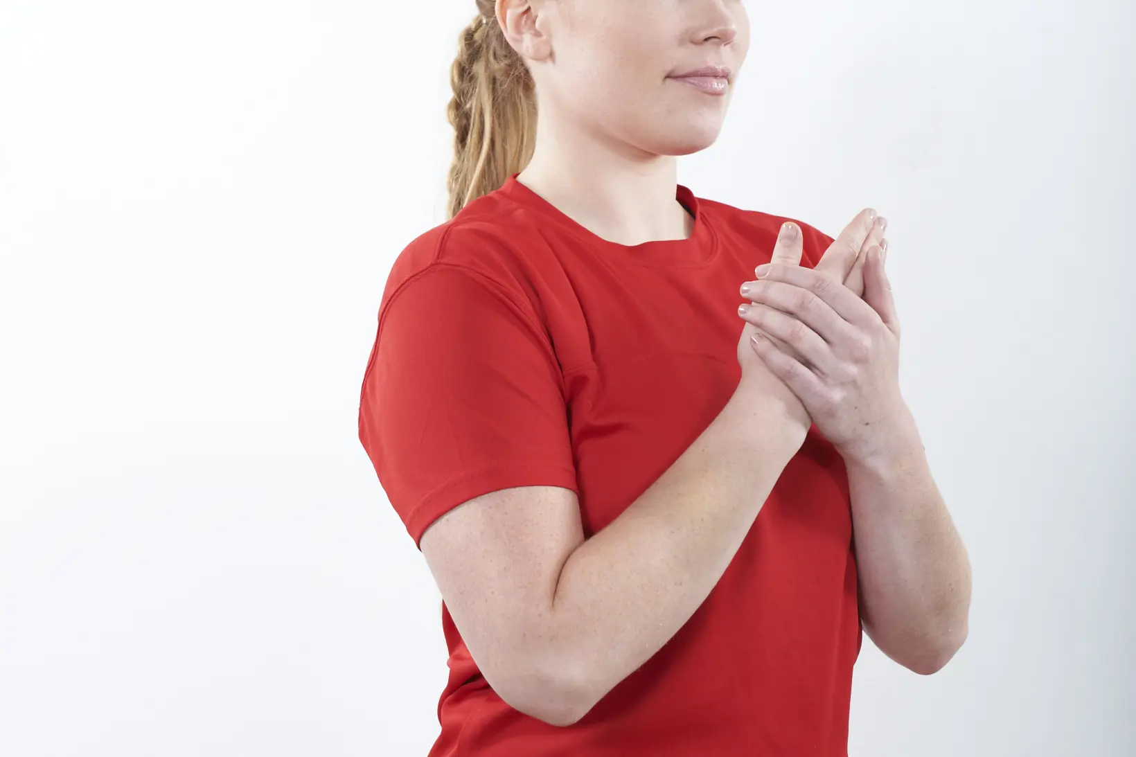 Dame som bøyer armen og holder hånden mot brystet og støtter med den andre hånden