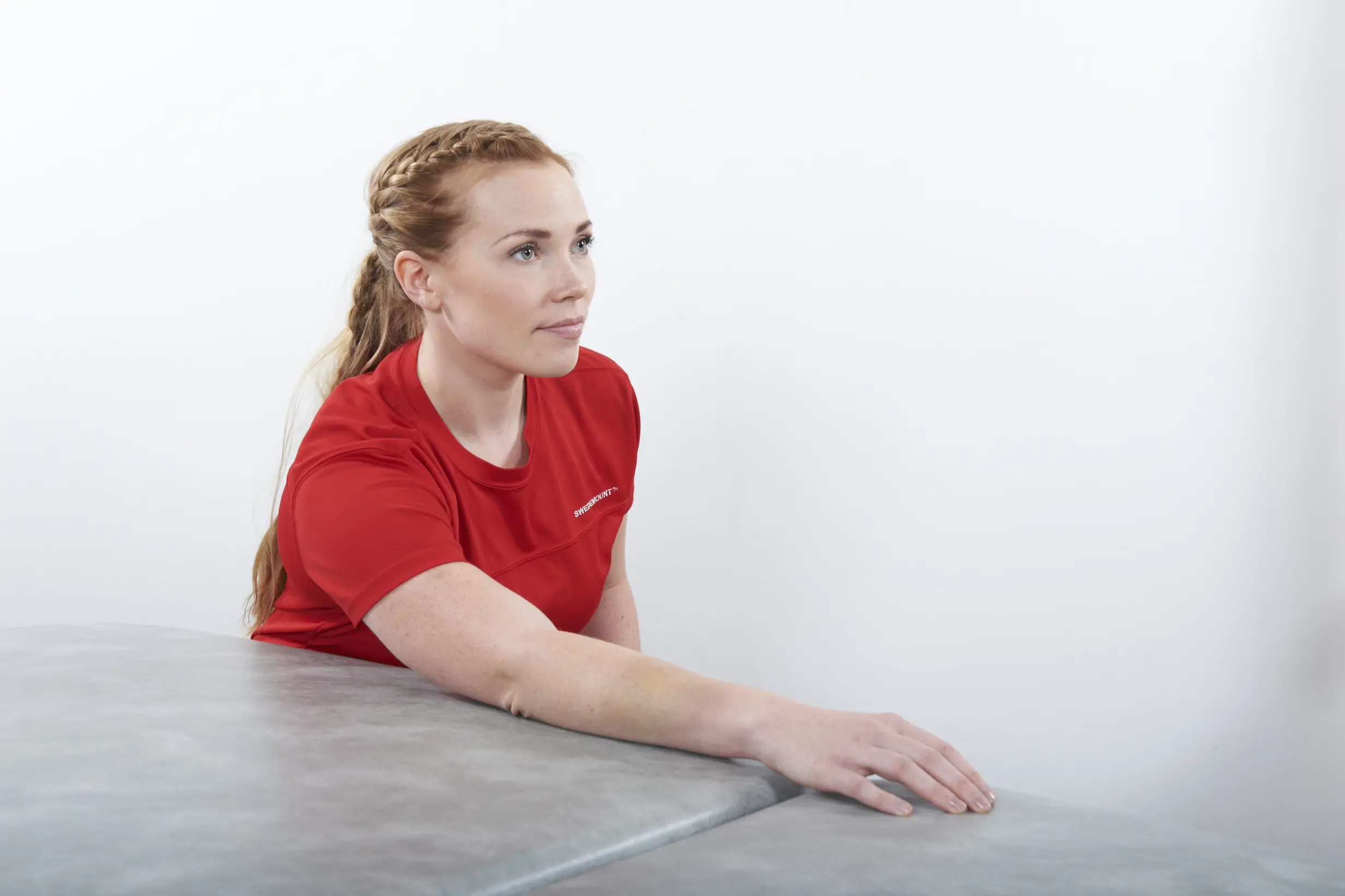 Dame som har underarmen liggende på et bord mens hun lener seg litt fremover