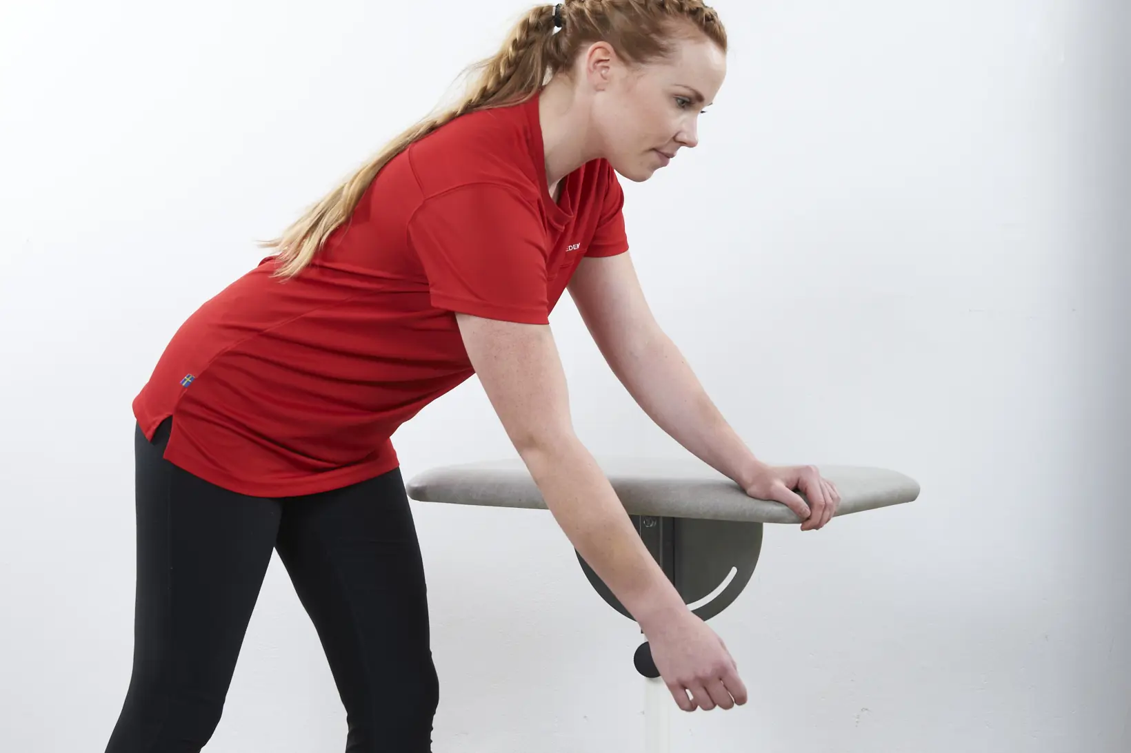 Dame som lener seg med en hånd mot et bord og den andre hånden henger ned