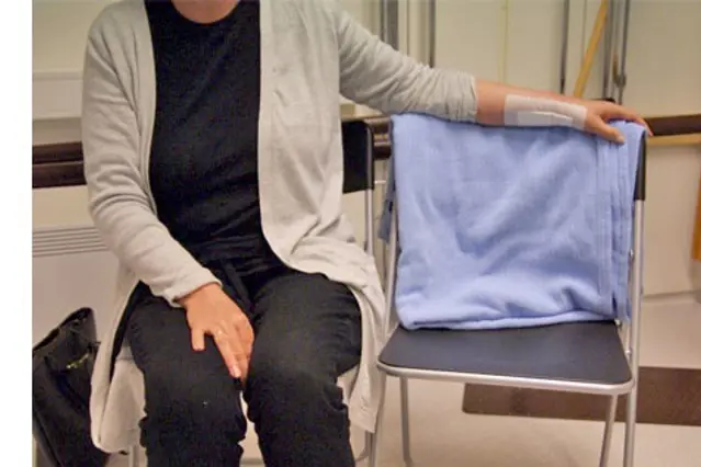 Hviler operert hånd på stolrygg. Foto