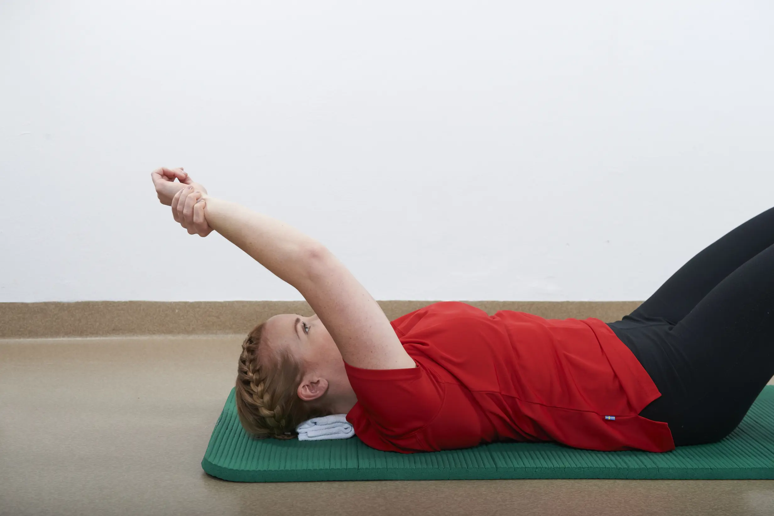 Dame som ligger på rygg med den opererte armen strukket opp