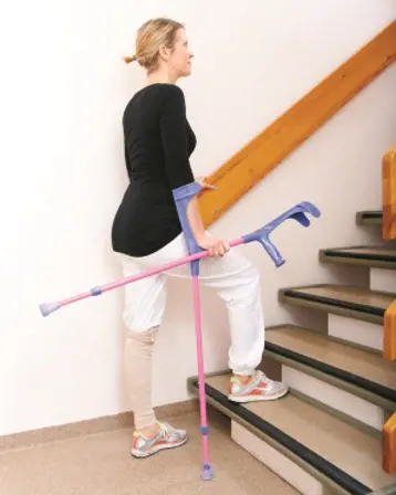 Dame går opp trapp med krykker. Bilde