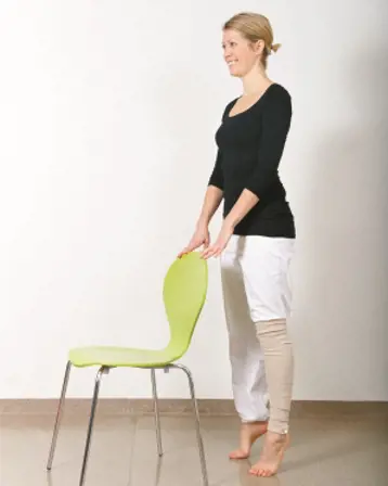Dame holder i en stol mens hun står på tærne