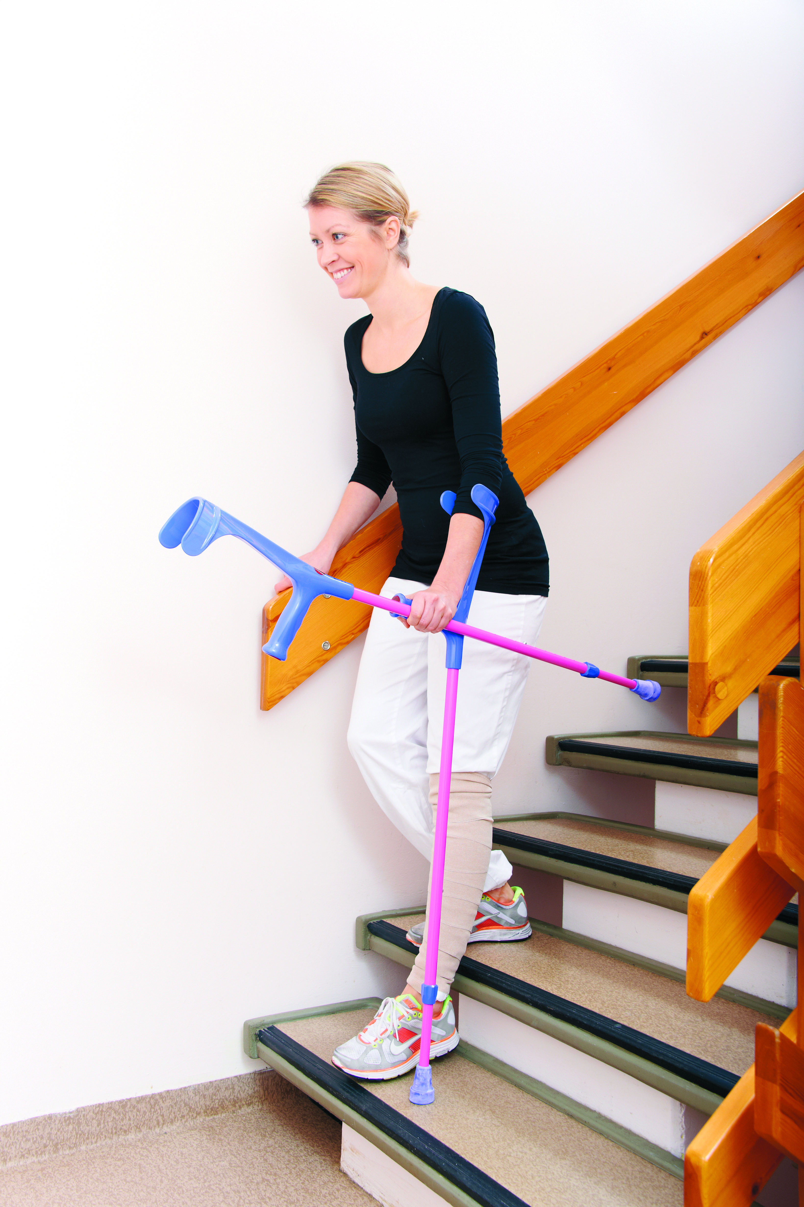 Ung dame med krykker viser hvordan man går ned en trapp