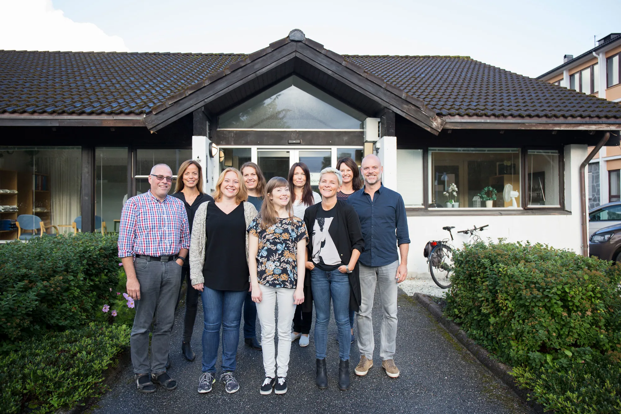 En gruppe mennesker som poserer for et bilde foran et hus