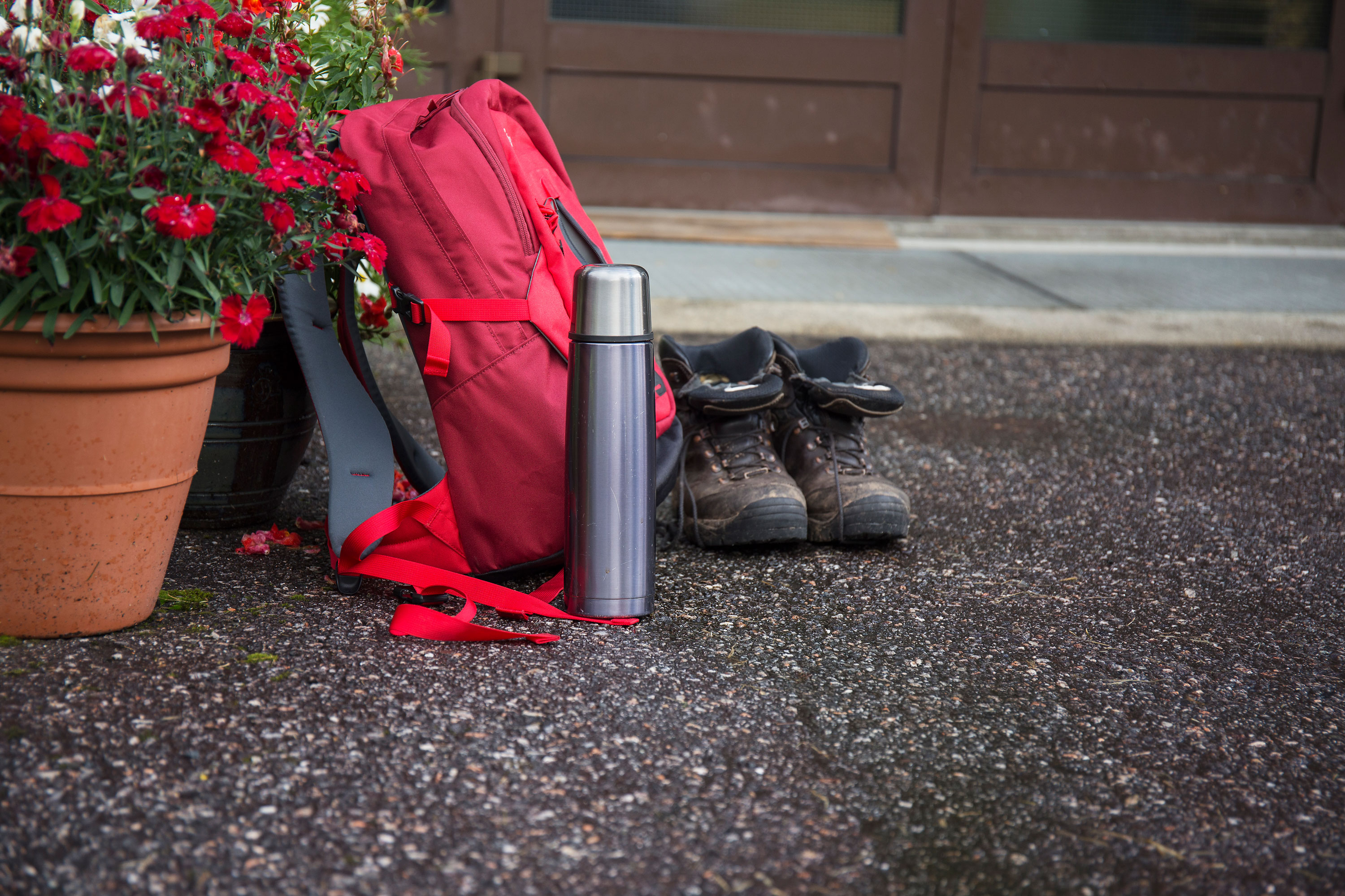 En rød koffert ved siden av et par støvler