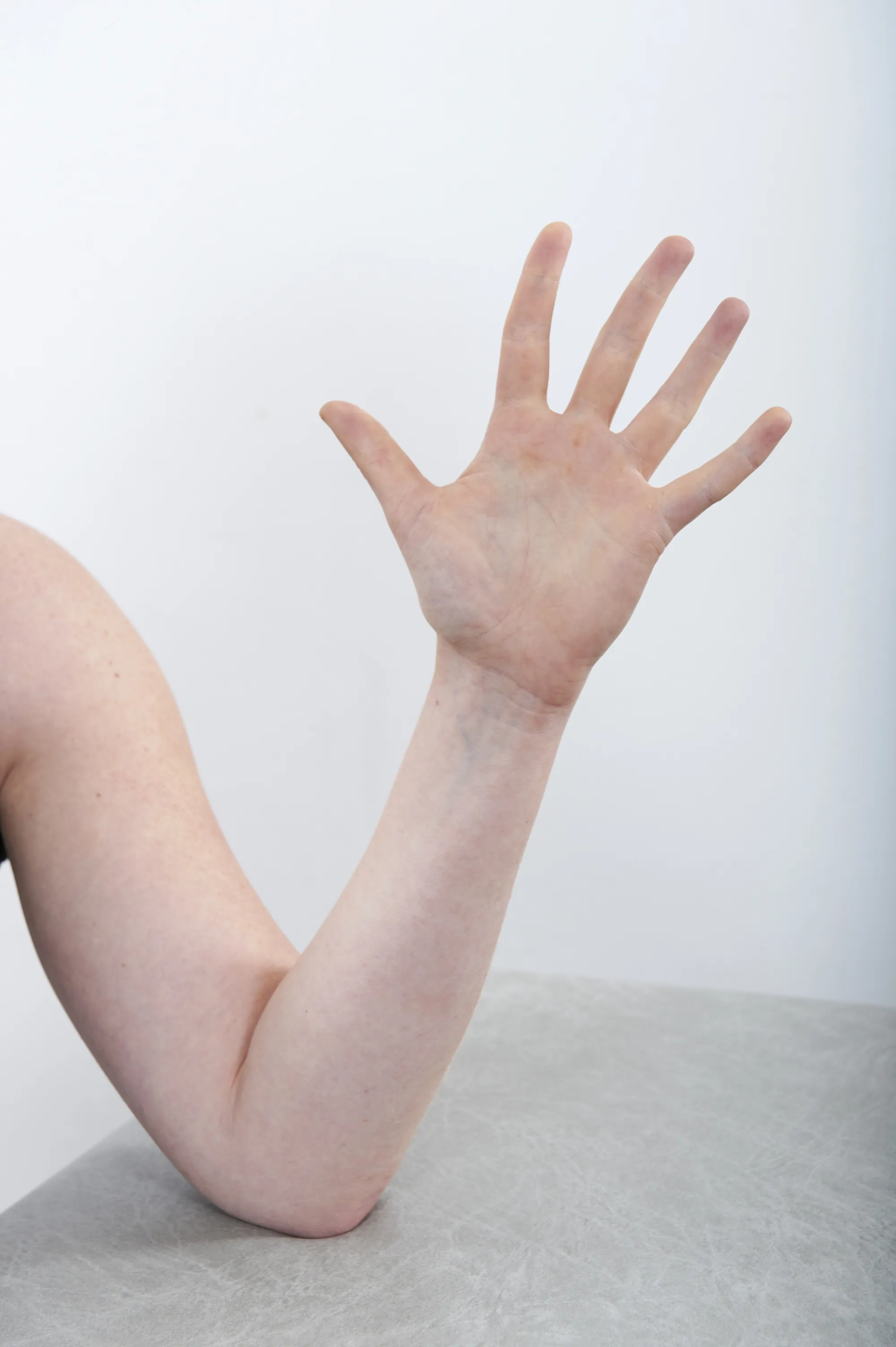 En hånd som spriker med fingrene med albuen hvilende på et bod