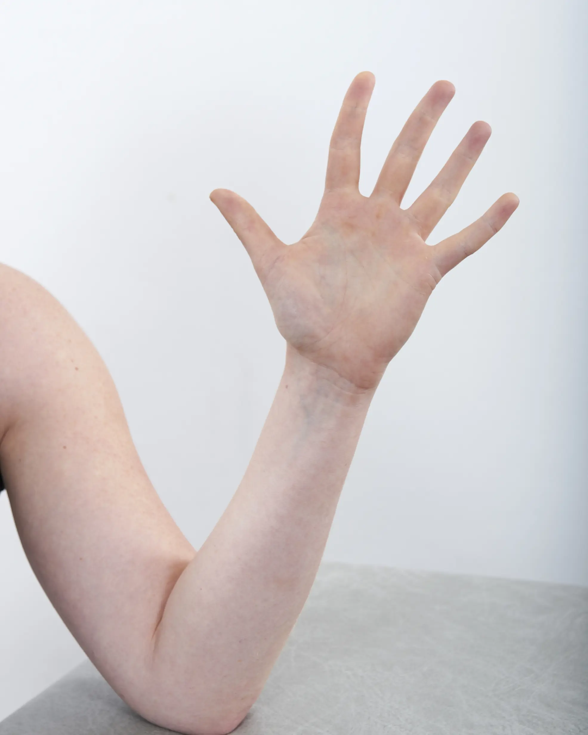 En hånd som spriker med fingrene med albuen hvilende på et bod