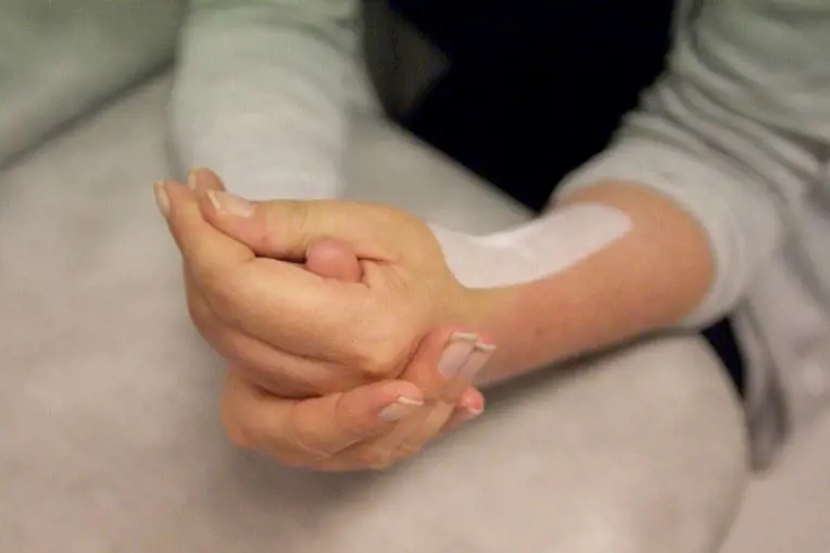 Frisk hånd hjelper oprert hånd med å knyte hånden. Foto