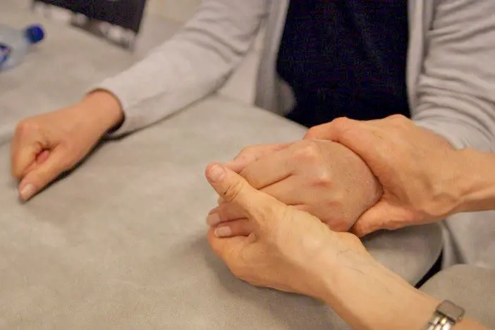 Fysioterapeut hjelper pasient med håndøvelser. Foto