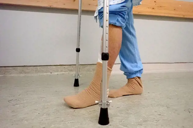 Person på krykker og fot med operert ankelledd berører gulvet. Foto