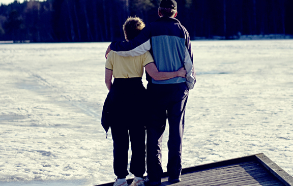 Et par ute på tur og holder rundt hverandre. Bilde.