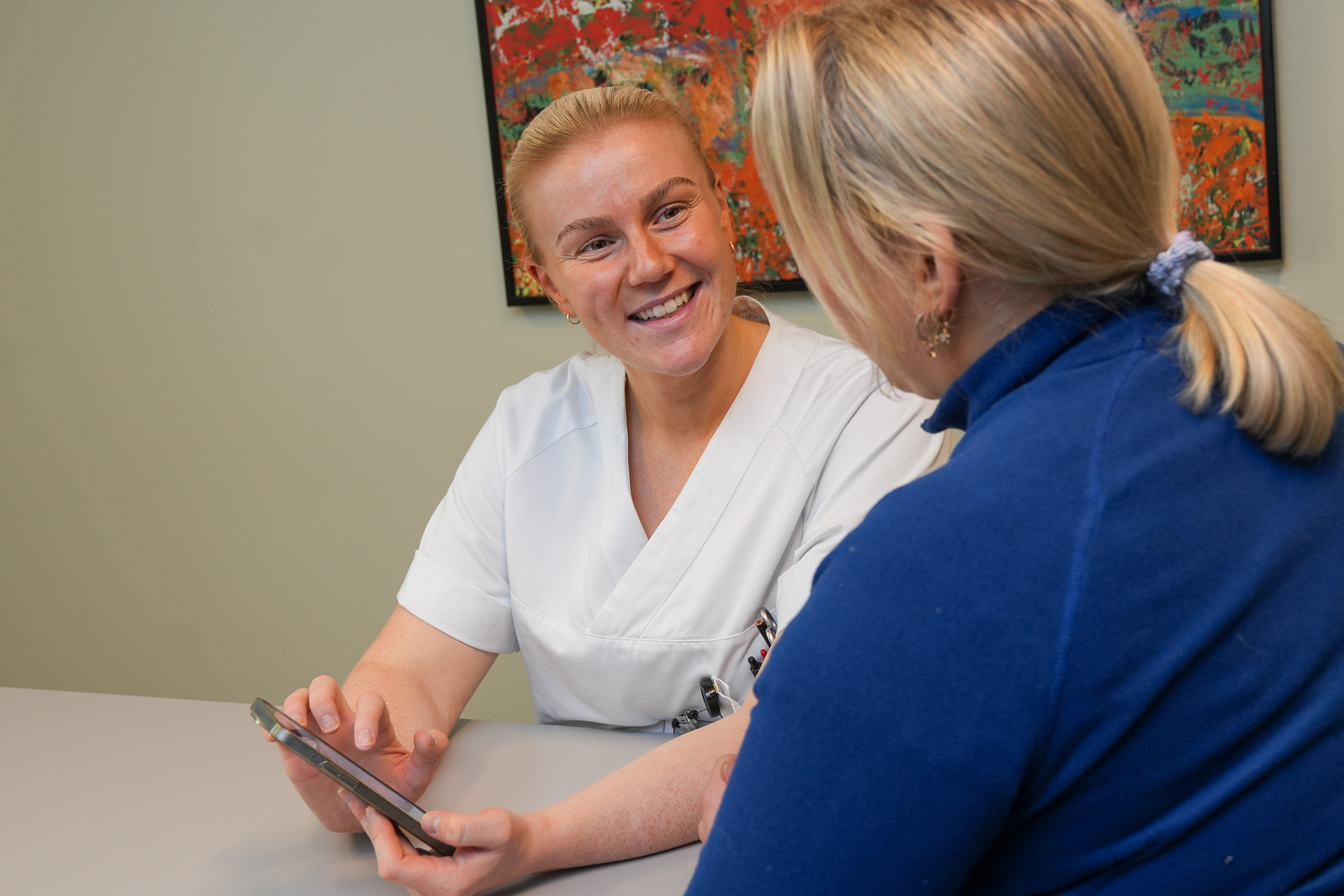 En person som viser en person noe på telefonen